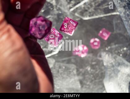 Set von rosa Rollenspiel Würfel fallen aus einem Hand auf Eisplatten in der Wintersonne Stockfoto