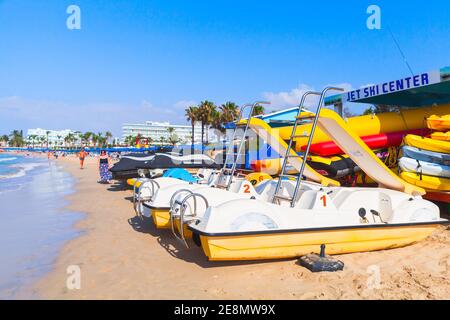 Ayia Napa, Zypern - 11. Juni 2018: Vergnügungsboote und Spaziergänger am Strand von Agia Napa. Resort Stadt am äußersten östlichen Ende der Südküste von C Stockfoto