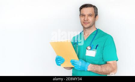 Attraktiver männlicher Arzt in blauem Anzug mit Stethoskop isoliert auf weißem Hintergrund Banner. Gutaussehender Arzt lächelt und hält den medizinischen Hist eines Patienten Stockfoto