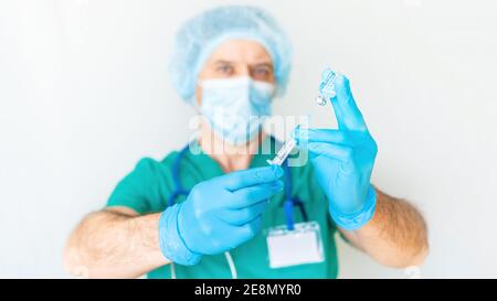 Strenger Arzt mit einer Spritze bereitet sich auf eine Injektion Nahaufnahme auf einem hellen Hintergrund zu machen. Angst vor Injektionen. Das Konzept der Angst vor Ärzten und Stockfoto
