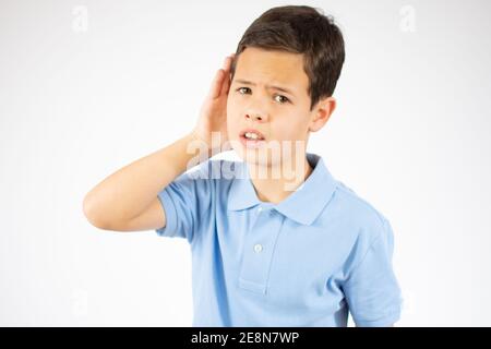 Was? Ich kann dich nicht hören. Portrait eines aufmerksamen neugierigen kleinen Jungen, der die Hand am Ohr hält und aufmerksam zuhört, was Sie sagen Stockfoto