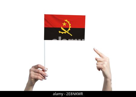 Eine schöne weibliche Hand hält eine Angola-Flagge, auf der sie den Finger ihrer anderen Hand zeigt, isoliert auf weißem Hintergrund Stockfoto