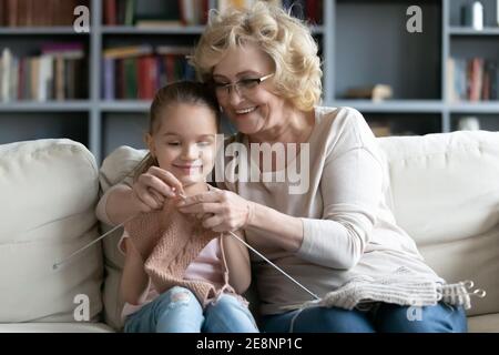 Glückliche Frau mittleren Alters unterrichtet kleine Vorschule Enkelin tun Handarbeiten. Stockfoto