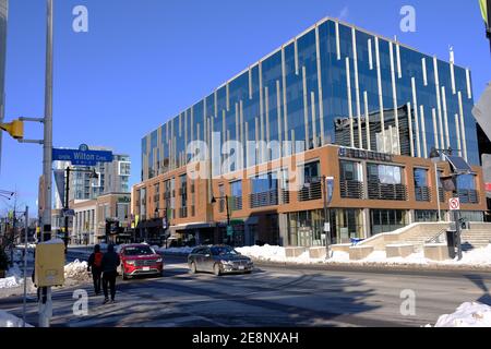 Interessantes Glasgebäude - Büros und Einkaufsmöglichkeiten - Teil des Lansdowne Park Komplexes an der Bank Street im Winter in Ottawa, Ontario, Kanada. Stockfoto