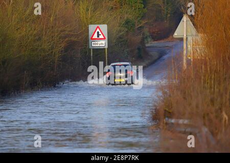 Ein Autofahrer fährt auf der Newton Lane in Fairburn durch das Flutwasser Nachdem er am 21. Januar von Storm Christoph überflutet wurde 2021 Stockfoto