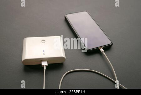Handy wird von der Powerbank aufgeladen. Isoliert. Auf schwarzem Hintergrund. Stockfoto