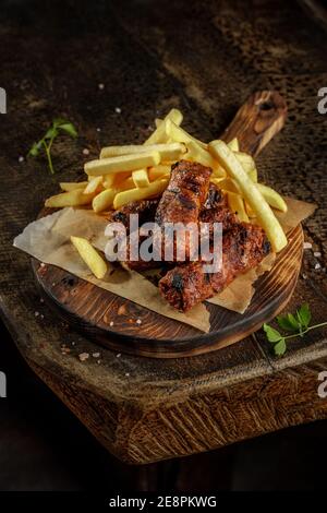 Grillhaus Konzept. Gegrillte, geröstete leckere Wurst mit pommes auf dem alten Holzschneidebrett. Stockfoto