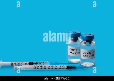 Coronavirus-COVID-19-Impfstoff. Fläschchen mit Spritzen isoliert auf blauem Hintergrund, Konzeptkomposition mit Kopierraum Stockfoto