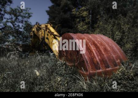 Alte verlassene Bagger mit großen rostigen Schaufel im Vordergrund Umgeben von grünen Pflanzen Stockfoto