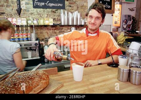 Ein männlicher Barista, der eine Tasse Kaffee mit einem Schuss Amaretto-Likör am Schalter des trendigen Cafés in East London Bricklane, Großbritannien, serviert. Stockfoto