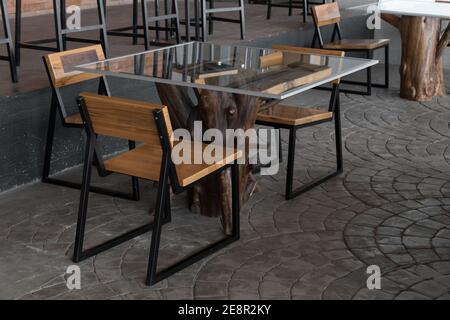 Detail eines Tisches mit Holzbalken und Glas, elegante Möbel in einer Cafeteria mit Tageslicht beleuchtet Stockfoto