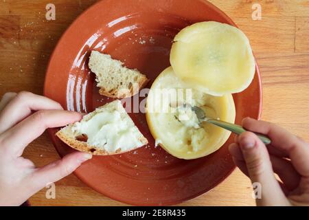 Frau Hände Speading weichen und cremigen Käse auf einem Stück Brot. Persönlicher Standpunkt Stockfoto