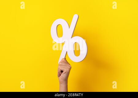 Hand hält Prozentzeichen über gelbem Hintergrund Stockfoto