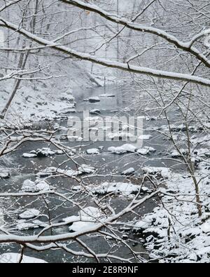 Blick auf Rock Creek in Washington, DC, mit schneebedeckten Felsbrocken und Bäumen. Stockfoto