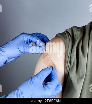 Medizinische Arbeiter setzen Band Hilfe auf männlichen Oberarm nach Coronavirus-Impfstoff erschossen Stockfoto