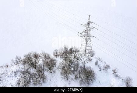 Hochspannungs-Pylon an der Küste des gefrorenen Sees im Winter an einem nebligen Tag. Luftaufnahme Stockfoto