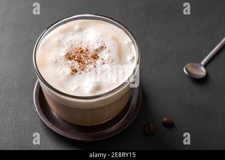 Cappuccino-Kaffee aus nächster Nähe. Frischer Kaffee mit köstlichem Milchschaum und Zimt auf dunklem Tisch. Stockfoto