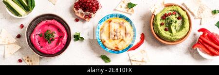 Bunte Hummusschüsseln, gesunde vegane Dips. Traditioneller mittelöstlicher Hummus, grüner Hummus, Beetwurzelhummus, verbreitet. Verschiedene Meze und Dips mit Pita Stockfoto