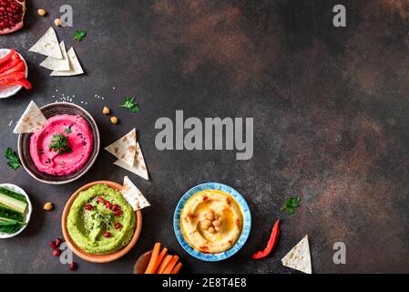 Bunte Hummusschüsseln, gesunde vegane Dips. Traditioneller mittelöstlicher Hummus, grüner Hummus, Beetwurzelhummus, verbreitet. Verschiedene Meze und Dips mit Pita Stockfoto
