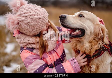 Kleines Mädchen umarmt goldenen Retriever Hund Stockfoto