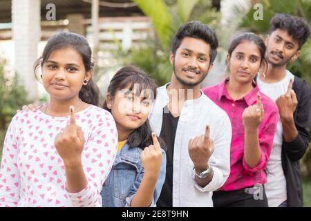 Eine Gruppe von Teenager-Freunden, die nach der Stimmabgabe mit Tinte markierte Finger außerhalb des Wahllokals oder des Messestandes zeigen - Konzept der indischen Wahl oder des Wahlwerfens Stockfoto