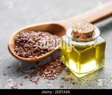 Leinsamen oder Leinsamen in Löffel mit Glas Leinsamen Öl auf Betongrund Stockfoto