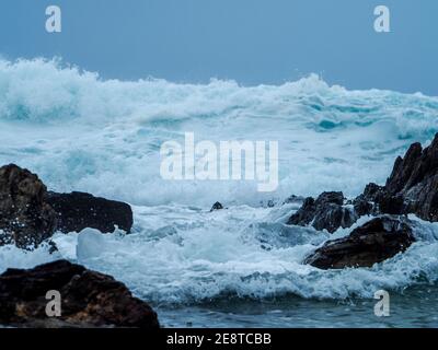 Schaumige, raue und schaumige, große Wellen Rollen ein und brechen und krachen über Felsen in der Nähe von Shore, Australien Stockfoto