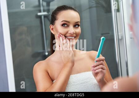 Frau auf der Suche nach Reflexion im Spiegel nach dem Duschen Stockfoto