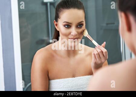 Frau Anwendung Make-up im Bad nach der Dusche Stockfoto