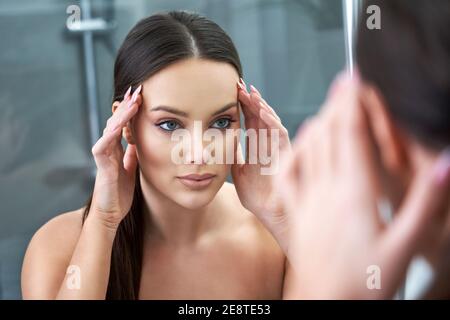 Frau auf der Suche nach Reflexion im Spiegel nach dem Duschen Stockfoto