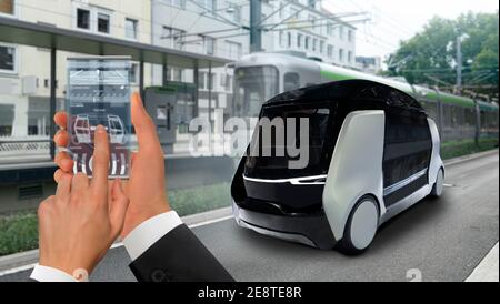 Steuerung von selbstfahrenden Taxi per Handy-App. Hand mit Telefon auf dem Hintergrund des autonomen Shuttles. Stockfoto