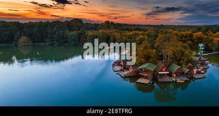 Tata, Ungarn - Luftpanorama eines schönen Herbstuntergangs über hölzernen Fischerhütten auf einer kleinen Insel am Derito-See (Derito-to) bei Tata i Stockfoto