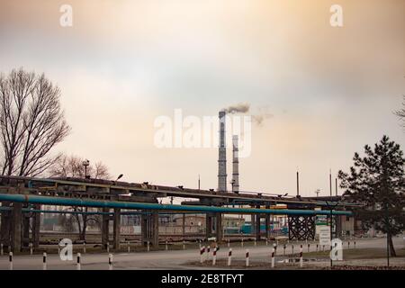 Industriezone mit zwei großen Rohren Rauch wird aus dem Werksrohr gegossen. Verschmutzung der Umwelt. Stockfoto