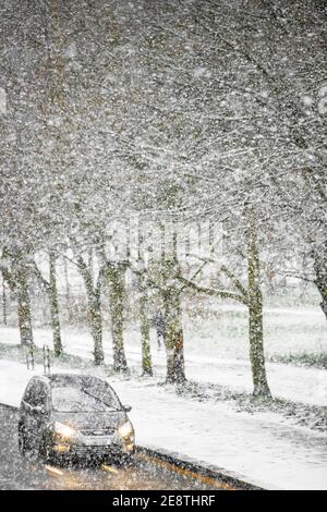 Ein Auto fährt mit eingeschalteten Scheinwerfern bei starkem Schnee Stockfoto