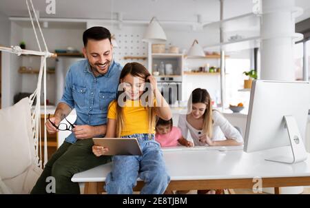 Eltern helfen Kindern, die online zu Hause studieren. Lockdown und Online-Schule, Technologie-Konzept. Stockfoto