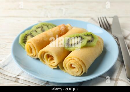 Konzept des Frühstücks mit Teller Crepes Brötchen mit Kiwi Scheiben auf Holztisch Stockfoto