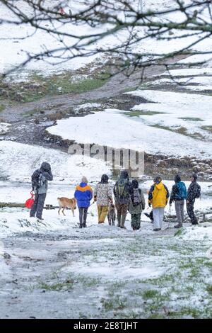 Eine Gruppe von Wanderern bereitet sich auf den Weg nach oben Rough Tor im Schnee auf Bodmin Moor in Cornwall. Stockfoto