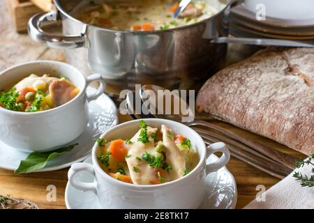 Hühnersuppe in Suppenschüsseln mit Topf serviert Und Löffel auf einem Tisch Stockfoto