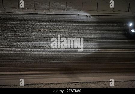 Berlin, Deutschland. Januar 2021. Die Scheinwerfer eines Autos beleuchten den Schnee auf der Straße. Das Auto fährt im Dunkeln auf einer verschneiten Straße in Berlin Mitte. Quelle: Annette Riedl/dpa/Alamy Live News Stockfoto
