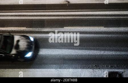 Berlin, Deutschland. Januar 2021. Ein Auto fährt im Dunkeln auf einer verschneiten Straße in Berlin Mitte. Die Scheinwerfer beleuchten den Schnee. Quelle: Annette Riedl/dpa/Alamy Live News Stockfoto