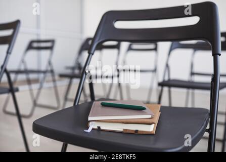 Grafik Hintergrundbild von Stift und Notizbuch auf schwarzem Stuhl im Publikum bei der Geschäftskonferenz, Kopierraum Stockfoto