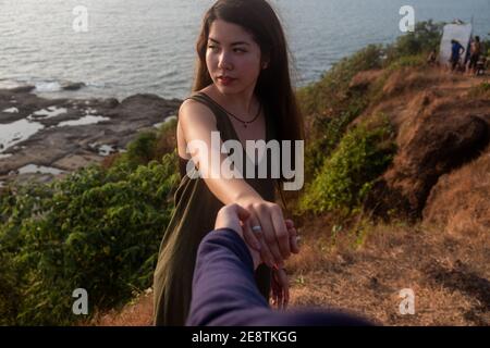 Aufnahme einer jungen Frau, die jemanden an der Hand am Strand führt Stockfoto