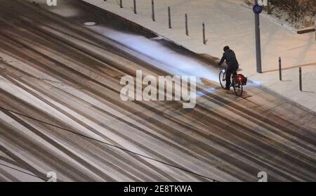 Berlin, Deutschland. Januar 2021. Ein Radfahrer fährt im Dunkeln auf einer verschneiten Straße in Berlin Mitte. Quelle: Annette Riedl/dpa/Alamy Live News Stockfoto