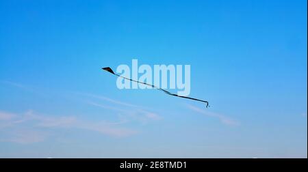 Schwarzer Stuntdrachen fliegt am blauen Himmel. Stockfoto