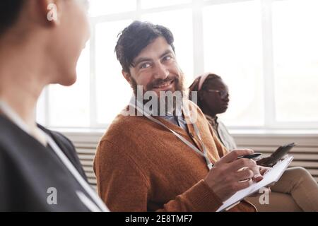Porträt eines lächelnden bärtigen Mannes im Publikum bei einer Konferenz oder bei einem Geschäftsseminar, Kopierraum Stockfoto