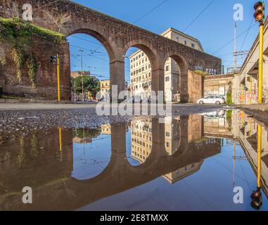 Häufige Regenschauer schaffen Pools, in denen sich die wunderbare Altstadt Roms wie in einem Spiegel spiegelt. Hier insbesondere Piazza di Porta Maggiore Stockfoto