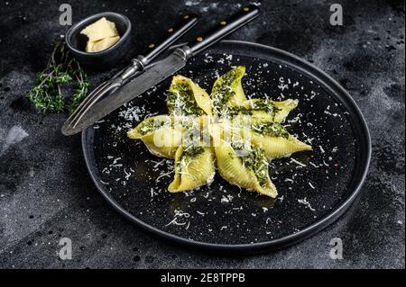Italienische Jumbo-Schalen Pasta Conchiglioni gefüllt mit Rindfleisch und Spinat auf einem Teller. Schwarzer Hintergrund. Draufsicht Stockfoto
