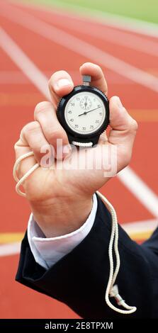 Die Zeit läuft - Geschäftsmann im Stadion hält Stoppuhr in Seine Hand - Nahaufnahme Stockfoto