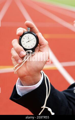 Die Zeit läuft - Geschäftsmann im Stadion hält Stoppuhr in Seine Hand - Nahaufnahme Stockfoto