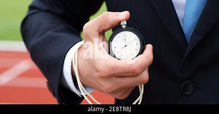 Die Zeit läuft - Geschäftsmann im Stadion hält Stoppuhr in Seine Hand - Nahaufnahme Stockfoto